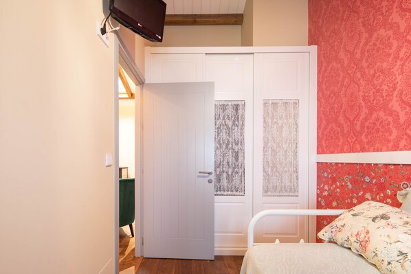 Un dormitorio con una cama, una puerta blanca y una pared con estampado rojo.