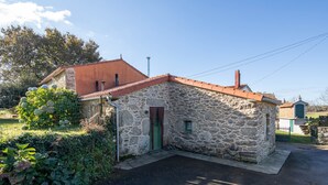 Un edificio de piedra con techo rojo, puerta verde y una ventana pequeña.