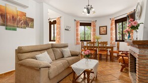 A living room with a sofa, dining table, chairs, a fireplace, and artwork on the walls.