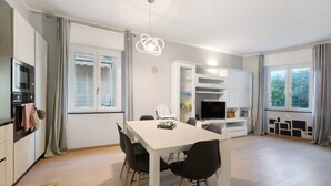 Een moderne keuken met een eethoek, een televisie en een raam met gordijnen.