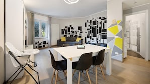 Een moderne keuken met een eetgedeelte, een kinderstoel en een wanddecoratie met geometrische vormen.