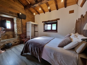 Une pièce confortable avec un lit, une chaise, une petite table, une fenêtre et un plafond en bois.