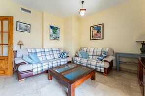 Uma sala de estar com dois sofás, uma mesa de centro e quadros nas paredes.