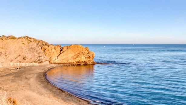 A coastal landscape with a sandy beach, rocky cliffs, and calm sea. - Apartment 'La Conque' with Air Conditioning (Agde)