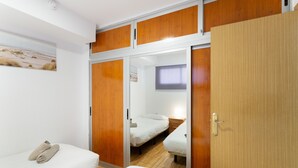 A bedroom with a bed, a bedside table, a wardrobe, and a mirror.