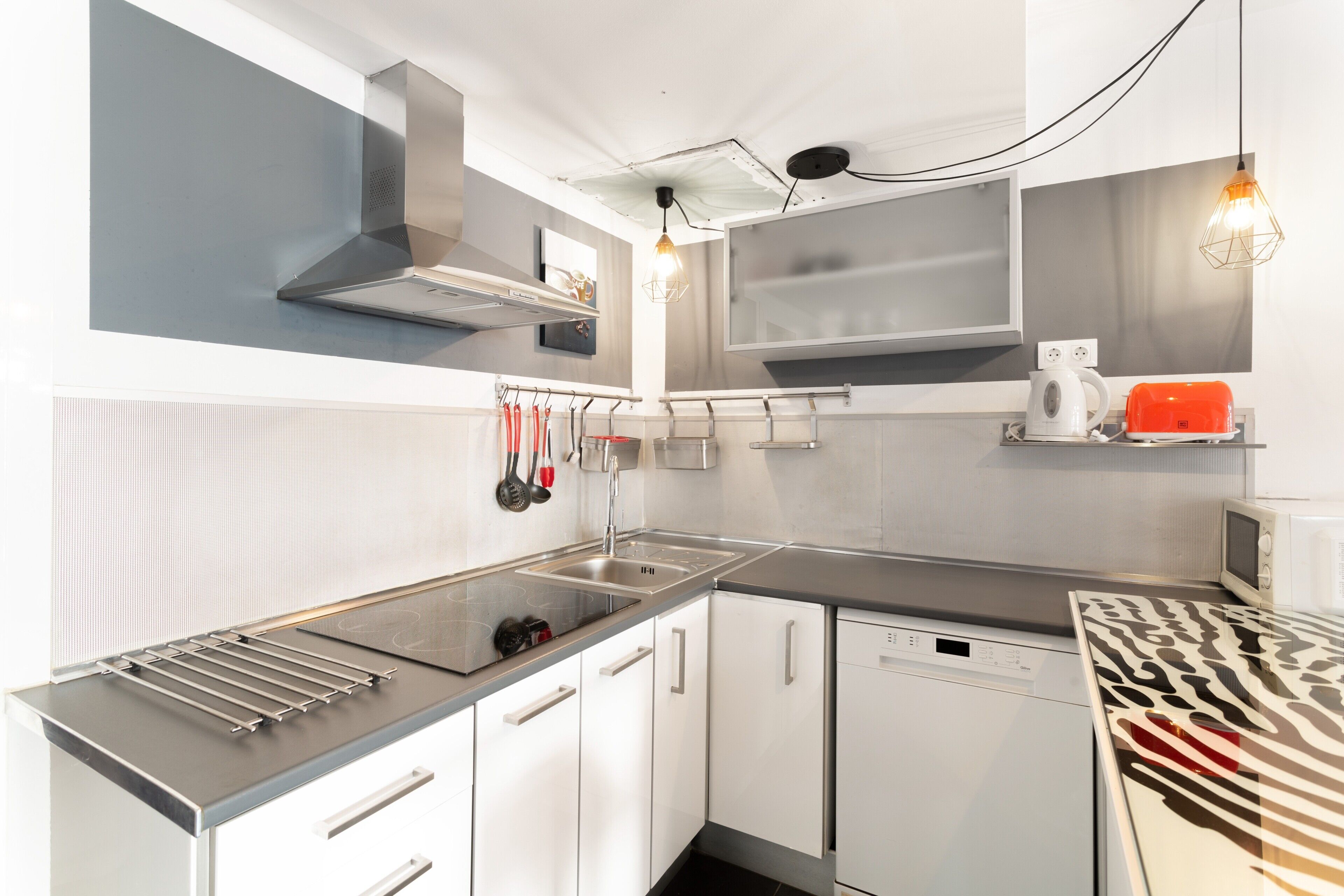 Una cocina moderna con electrodomésticos de acero inoxidable, armarios blancos y una mesa con estampado de cebra.