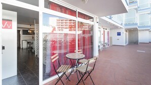 Un patio interior con una partición de vidrio, una mesa redonda y cuatro sillas de madera.