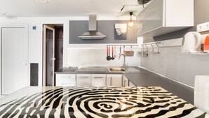 Una cocina moderna con piso estampado de cebra, electrodomésticos de acero inoxidable y un colgador para ollas.