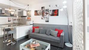 Una cocina moderna con barra, un sofá gris con cojines rojos y arte abstracto en la pared.