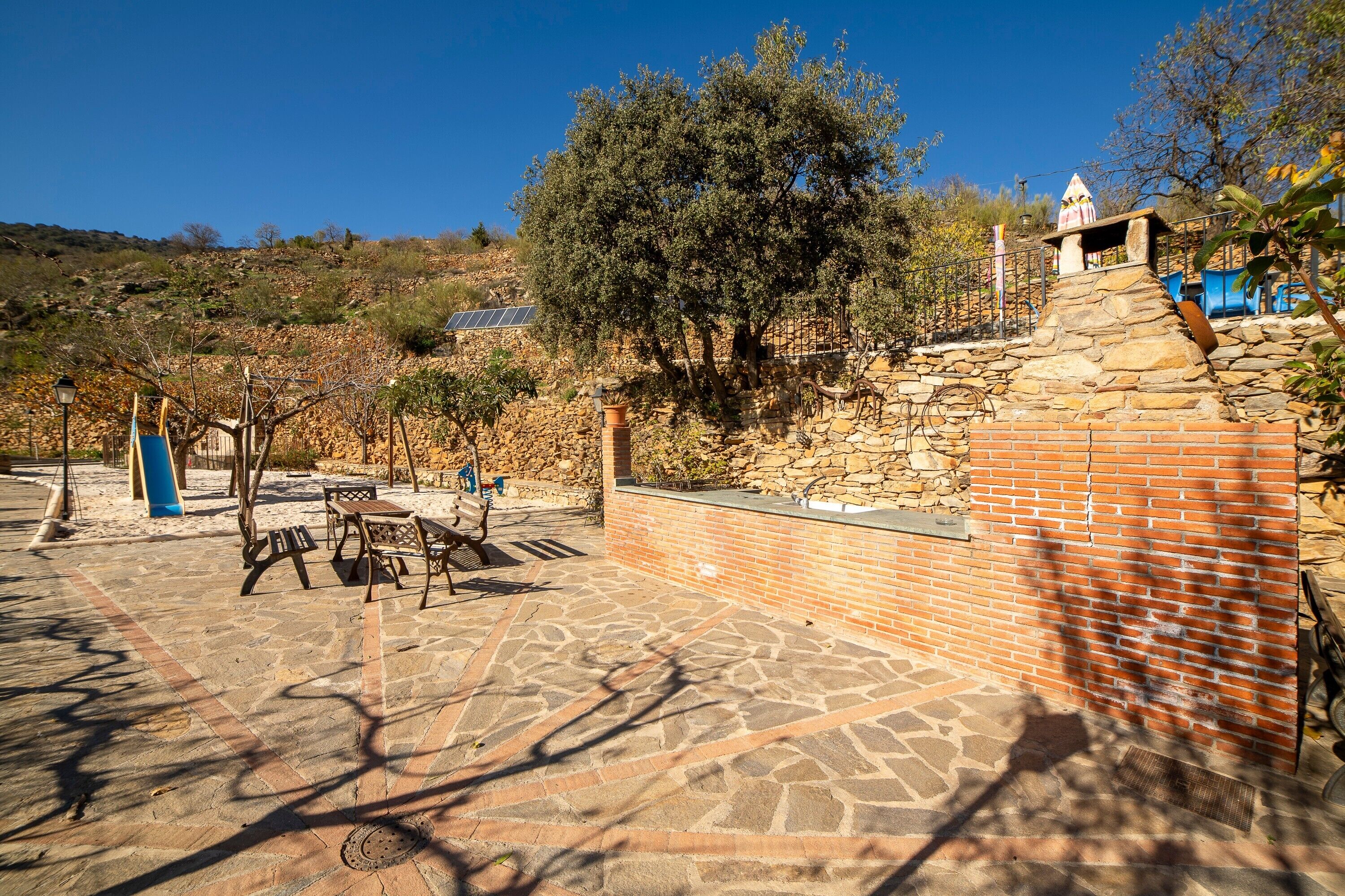 Un espace extérieur aménagé en terrasse, avec un sol en pierre, un mur en briques et un banc en pierre.