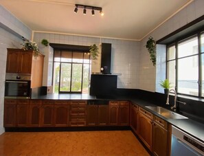 Une cuisine moderne avec des meubles en bois, un plan de travail noir, un four encastré et une fenêtre offrant une belle vue.