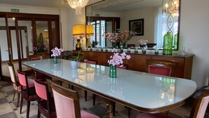 Et spiseområde med et langt bord, stole, en lysekrone og et spejl.