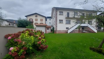 Un edificio residencial con un césped cuidado y un pequeño jardín de flores rosadas.