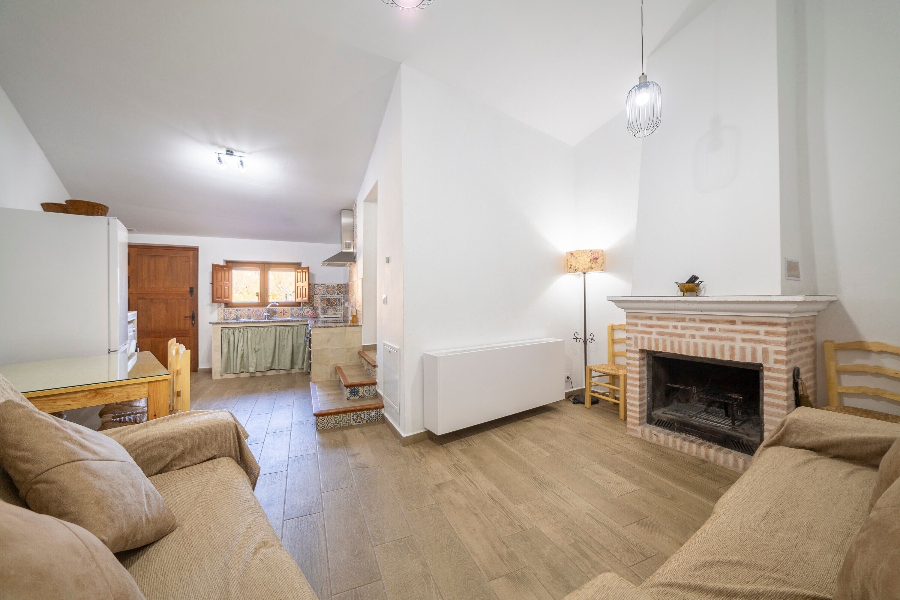 Una sala de estar con chimenea, un comedor y una cocina al fondo.