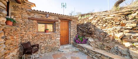 A stone building with a wooden door, a window, and a stone wall.