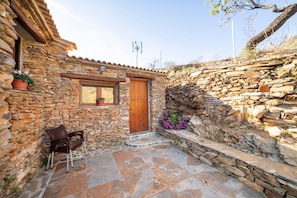 A stone building with a wooden door, a window, and a stone wall.