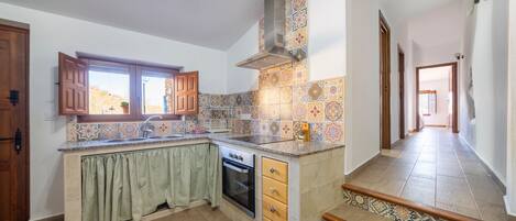 A kitchen with a window, wooden cabinets, a stove, and a tiled backsplash.