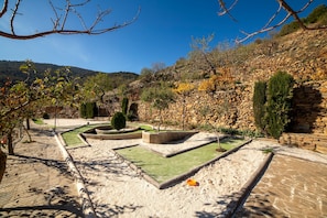 A landscaped garden with stone walls, pathways, and various plants.