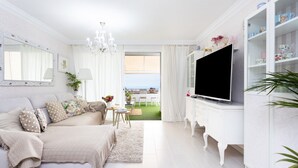A modern living room with a sofa, TV, and white cabinetry.