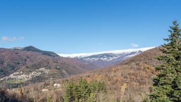 Paesaggio montuoso con un villaggio immerso nella valle, circondato da colline ricoperte di boschi.