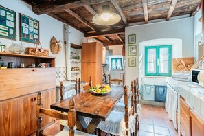 Una cucina rustica con mobili in legno, un tavolo da pranzo con sedie e una ciotola di frutta.