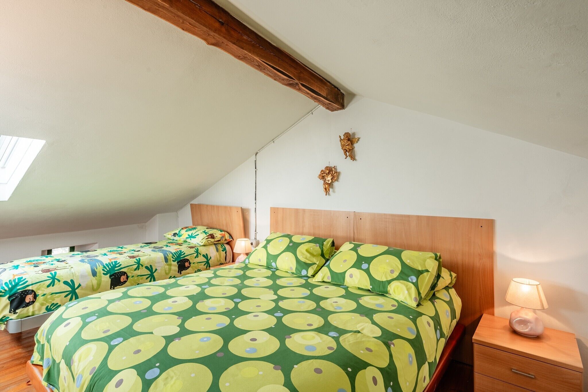 Une chambre avec deux lits, des têtes de lit en bois, une table de chevet avec une lampe et un luminaire fixé au mur.