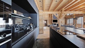 Une cuisine moderne avec des meubles de couleur sombre, des appareils électroménagers en acier inoxydable et un plafond en bois.