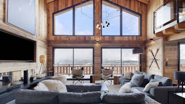 Un vaste espace de vie doté d’un grand téléviseur à écran plat, de canapés gris et d’un décor intérieur en bois.