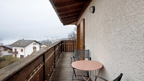 Ein Balkon mit Holzgeländer, einem Tisch und zwei Stühlen.