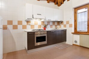 A modern kitchen with a built-in oven, a gas stove, and a window with a view. - Apartment 'Casa Pòlse' with Mountain View, Shared Garden and Wi-Fi (Baselga di Pinè)