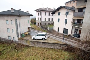 Un quartier résidentiel avec un fourgon blanc garé sur une allée en pente, des maisons dotées de balcons et un mur en pierre.
