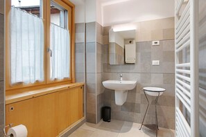Une salle de bain avec un meuble en bois, un lavabo, un miroir, un porte-serviettes et un porte-rouleau de papier toilette.