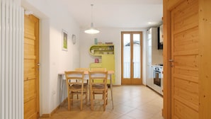 Une cuisine avec une table et des chaises, un meuble jaune et une porte en bois.
