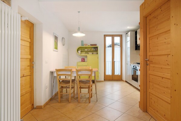 A kitchen with a dining table and chairs, a yellow cabinet, and a wooden door.