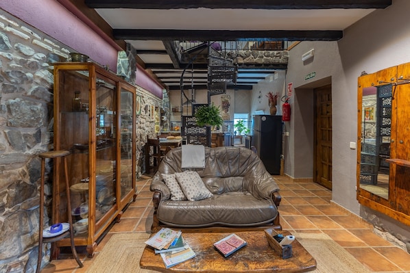 Ein gemütlicher Innenraum mit Ledersofa, Holztisch und Steinwand.