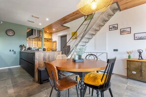 Un espace repas comprenant une table ronde en bois, des chaises et un escalier.