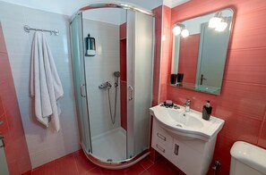 Ein Badezimmer mit Duschkabine, weißem Waschbecken, Spiegel und Handtuchhalter.