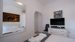 Een moderne hotelkamer met een bed, een grote spiegel, een flatscreen televisie, een dressoir en kunst aan de muur.