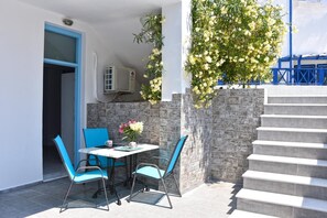 A patio with a table and chairs, a staircase, and a wall with a climbing plant. - Apartment 'Economy Semi-basement 1' with Private Terrace, Wi-Fi (Santorini)