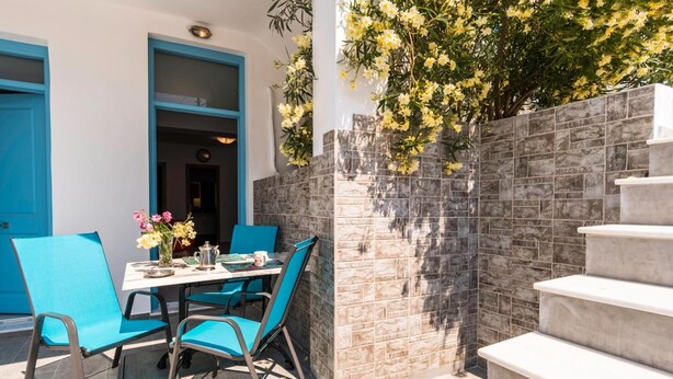 Un espace extérieur aménagé pour les repas, avec une table et des chaises, un mur en pierre et un escalier.
