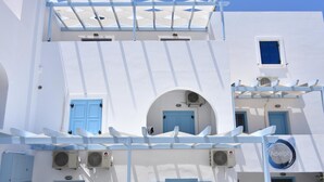 Un bâtiment blanc avec des portes et des fenêtres bleues, des unités de climatisation et une enseigne portant le nom « Adelphi ».
