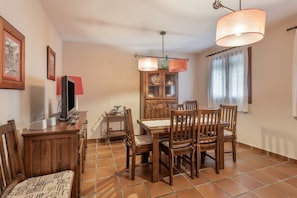 A dining area with wooden furniture, a cabinet with dishes, and a television.