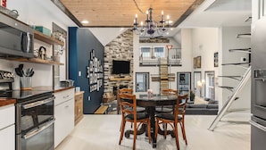 Una cocina moderna con comedor, que incluye una araña, armarios de madera y una chimenea de piedra.