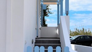 A white building with blue accents, a staircase, and a car parked outside. - Apartment '3  44' with Mountain View, Wi-Fi and Air Conditioning (Santorini)