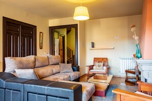 A living room with a sofa, coffee table, and a chair. There is a staircase leading to another room.