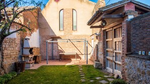 A courtyard with a brick building, a wooden pergola, and a stone wall.