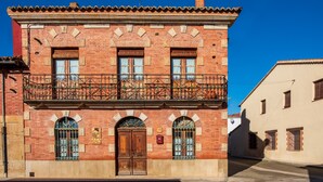 A two-story building with a balcony, arched windows, and a wooden door.