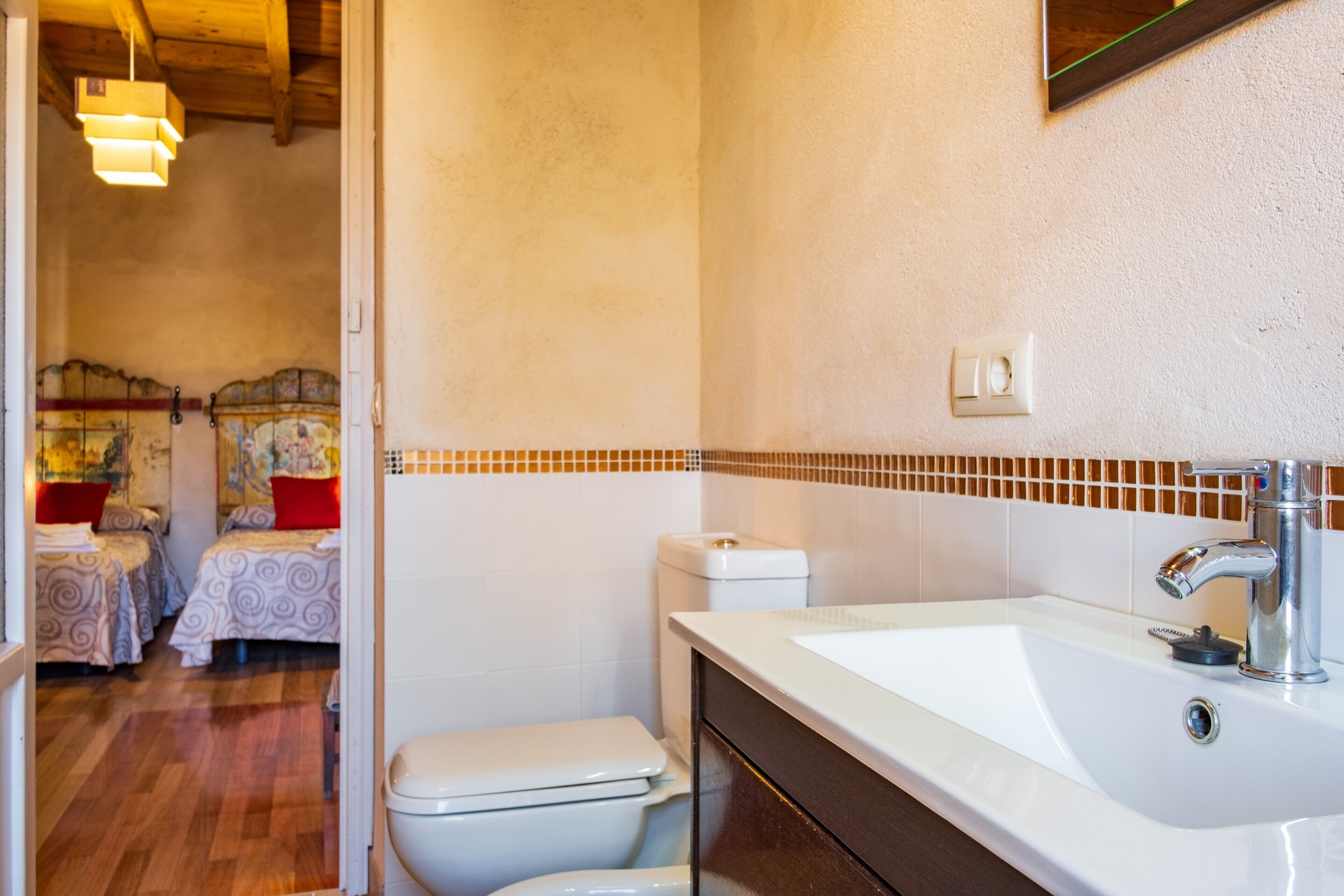 Un baño con un lavamanos blanco, un espejo y un inodoro.