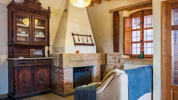 A room with a fireplace, a cabinet, a sofa, and a window with wooden shutters.