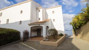 Un edificio blanco con techo de tejas y un porche, con vista al mar.